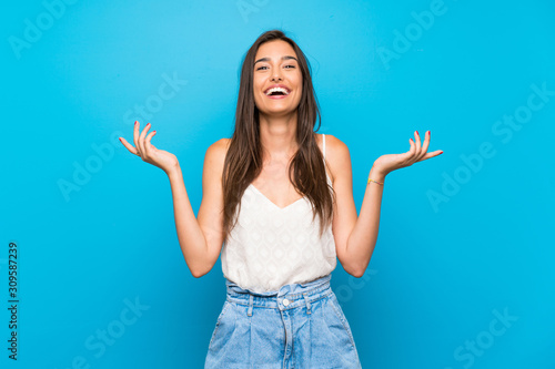 Young woman over isolated blue background smiling a lot