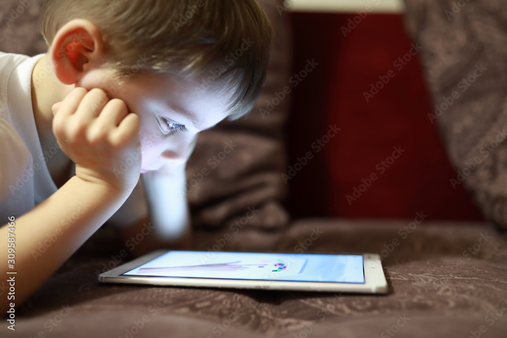 Child with tablet on sofa - obrazy, fototapety, plakaty 