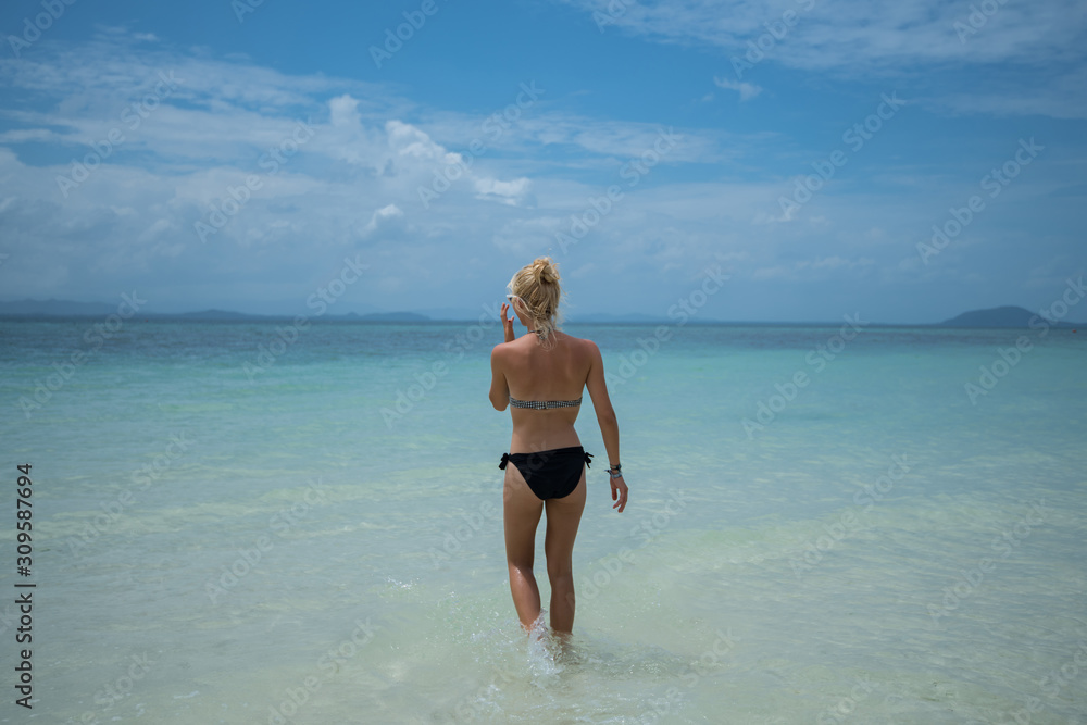 Beautiful young female in bikini on gorgeous sandy beach enjoying summer time vacation