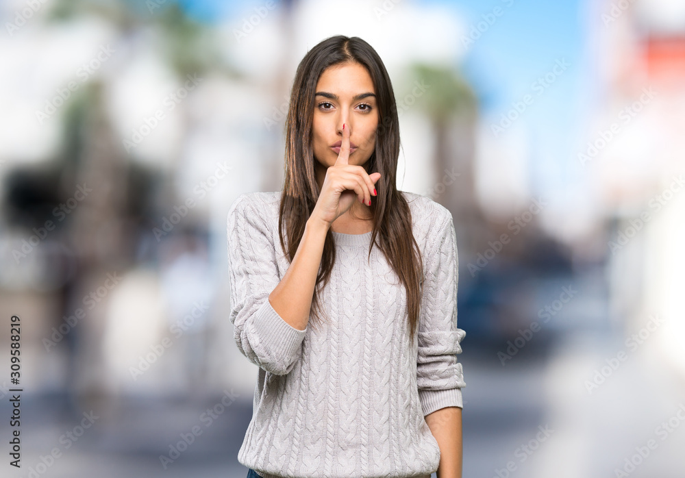 Young hispanic brunette woman showing a sign of silence gesture putting finger in mouth at outdoors Young hispanic brunette woman showing a sign of silence gesture putting finger in mouth at outdoors