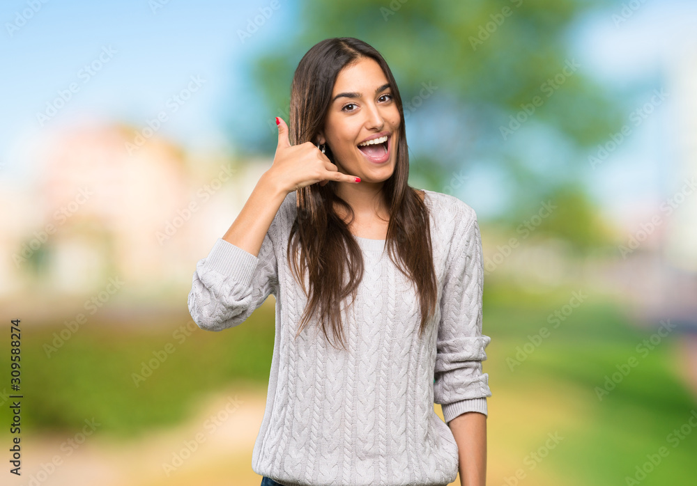 Young hispanic brunette woman making phone gesture. Call me back sign at outdoors
