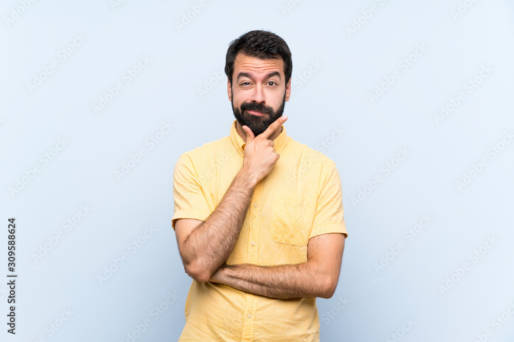 Fototapeta premium Young man with beard over isolated blue background thinking