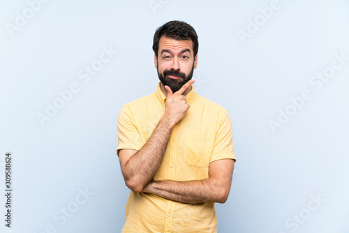 Young man with beard over isolated blue background thinking