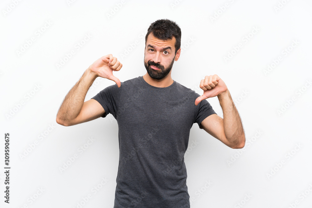 Young handsome man over isolated white background showing thumb down Young handsome man over isolated white background showing thumb down