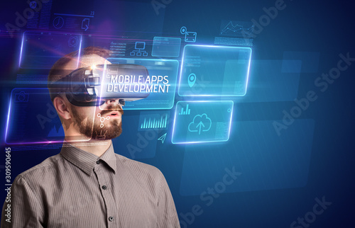 Businessman looking through Virtual Reality glasses with MOBILE APPS DEVELOPMENT inscription, new technology concept