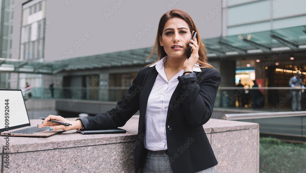 Respectable businesswoman using laptop during phone conversation Respectable businesswoman using laptop during phone conversation