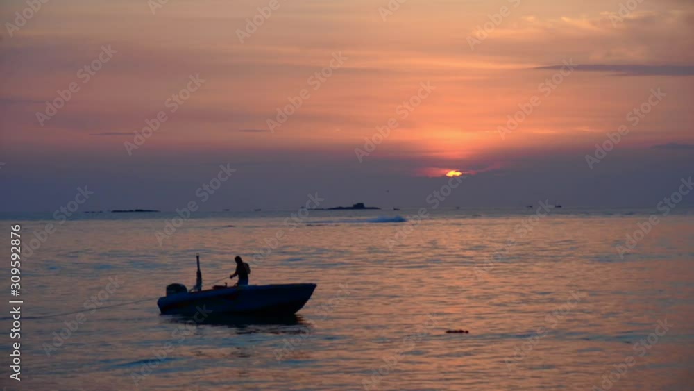Fisherman on his boat  on the sea at sunset