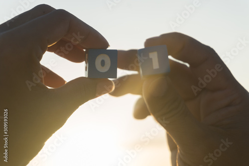 Man and women holds a Number zero and one in hands, sunset, sea background. photo