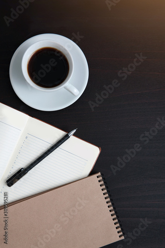 Black coffee in a white Cup and a notebook with a pen on a dark table. The view from the top. Things, items for storing and recording information.
