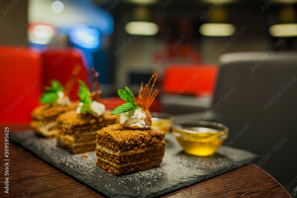 Delicious honey cake with salted caramel dripping from the top layer. Brown dessert with cream. Served in a white plate. Delicious honey cake with salted caramel dripping from the top layer. Brown dessert with cream. Served in a white plate.