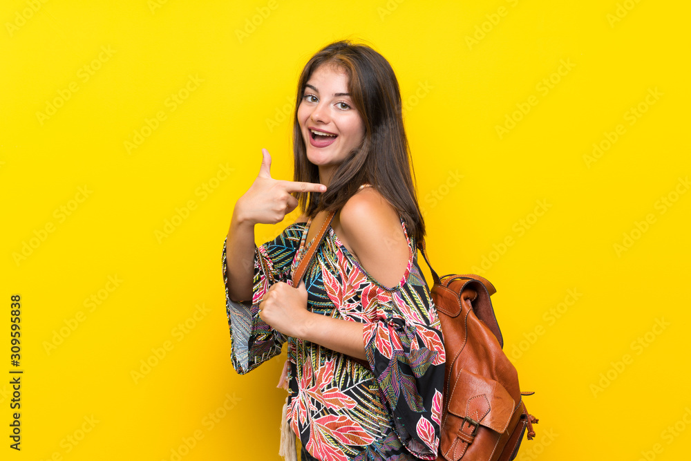 Caucasian girl in colorful dress over isolated yellow background with backpack Caucasian girl in colorful dress over isolated yellow background with backpack