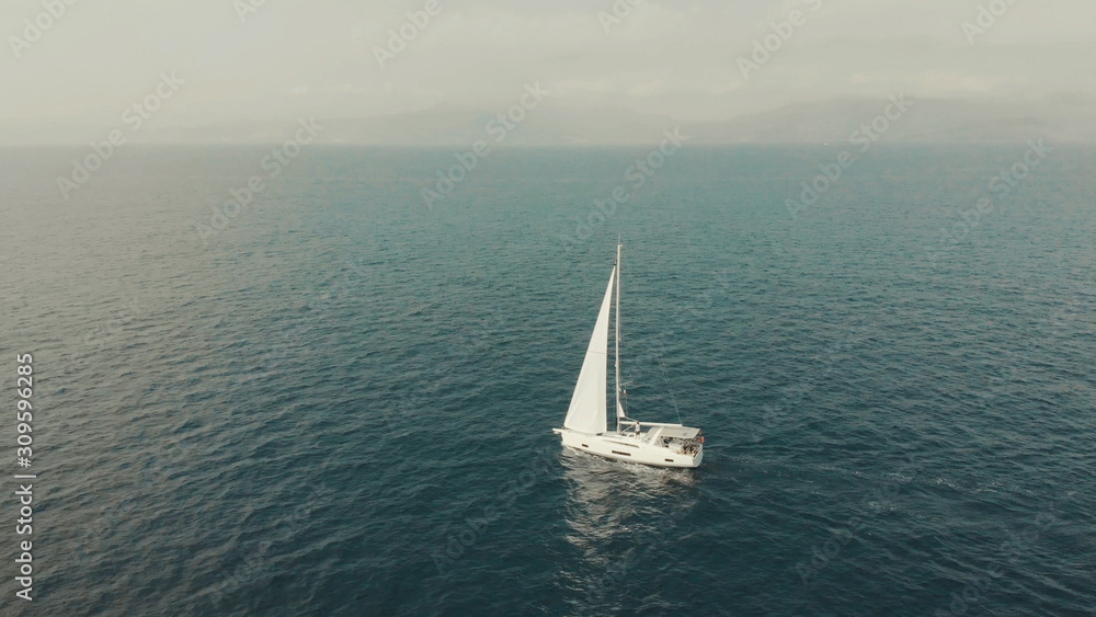 Aerial View of yacht in ocean. Drone footage of yachting around Balearic islands in the mediterranean sea. Silhouette of people