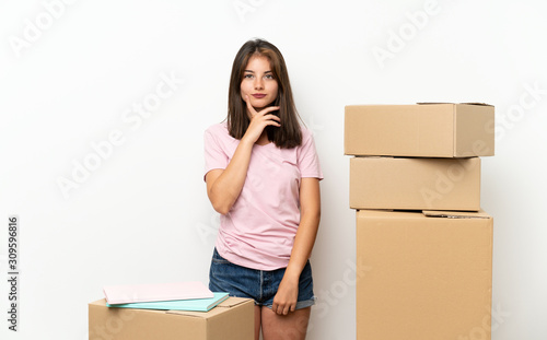 Young girl moving in new home among boxes thinking an idea