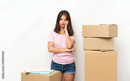 Young girl moving in new home among boxes unhappy and frustrated © luismolinero