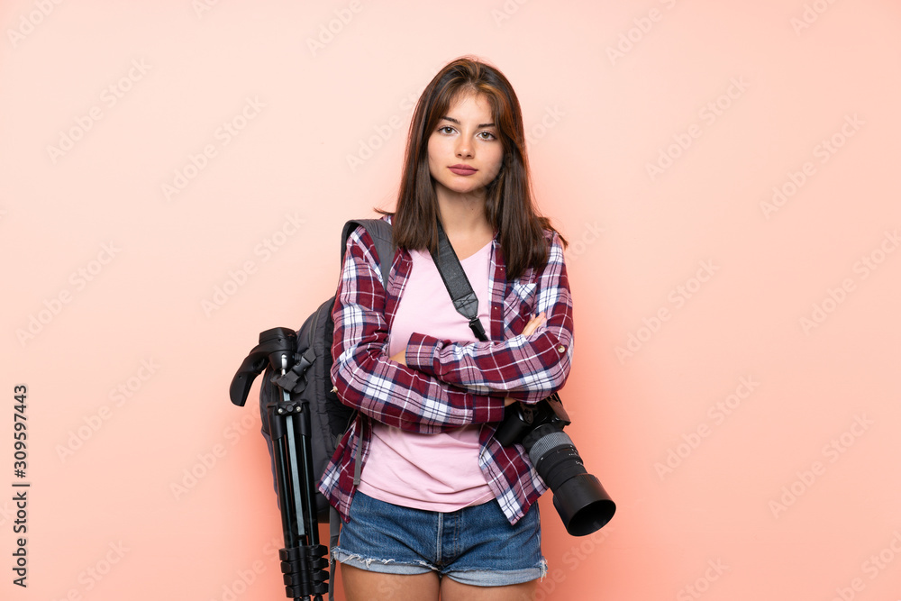 Young photographer girl over isolated pink background keeping arms crossed Young photographer girl over isolated pink background keeping arms crossed
