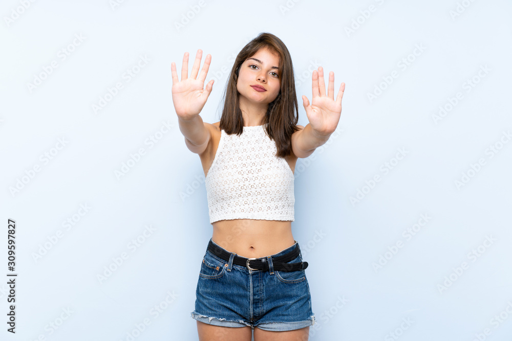 Young woman over isolated blue background making stop gesture and disappointed Young woman over isolated blue background making stop gesture and disappointed