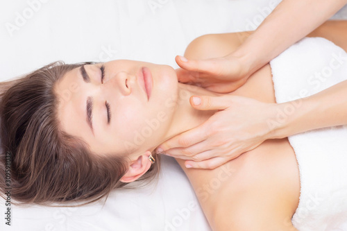 massage and stretching of the cervical muscles. Beautiful girl gets massage in a spa salon. light tones photos. concept of massage and health. rheumatism, arthrosis