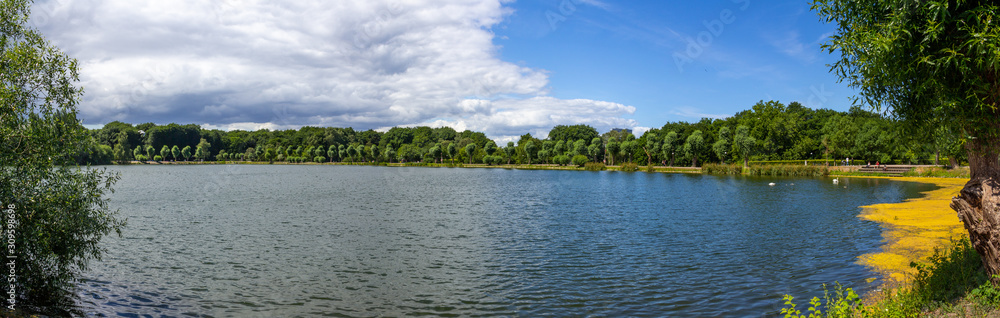 Panoramic view over the lake in the public park Pildammsparken in Malmö, Sweden, during a summer day when clouds are building up on the horizon