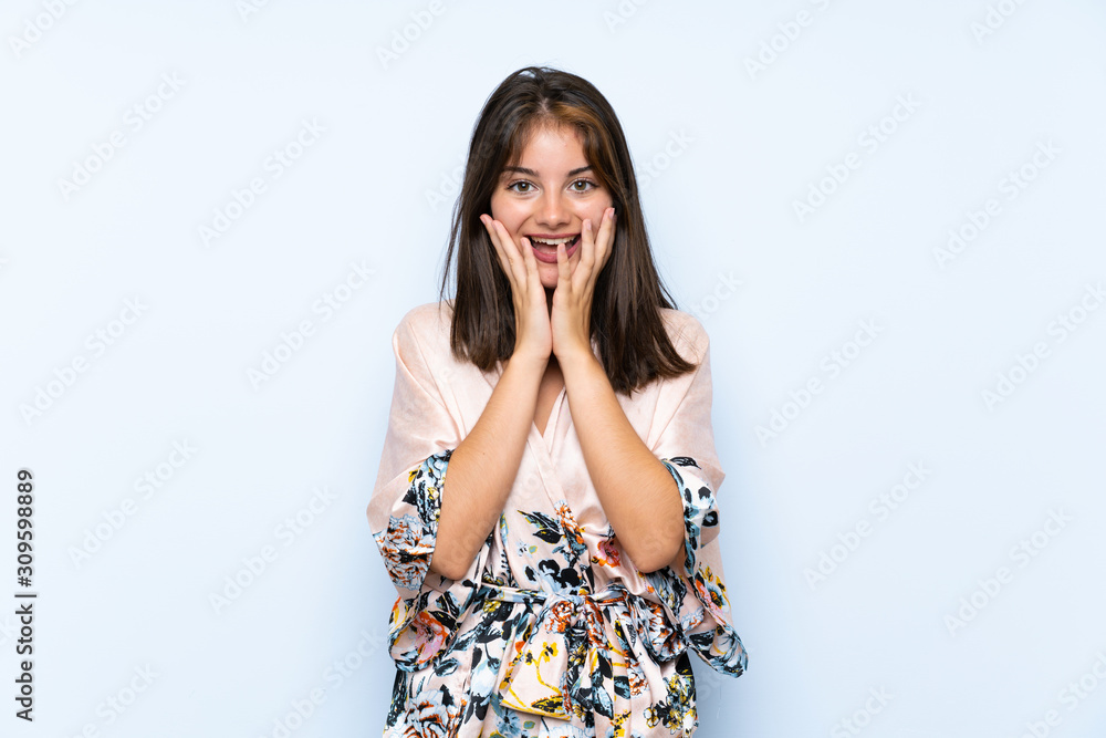 Caucasian girl with kimono over isolated blue background with surprise facial expression Caucasian girl with kimono over isolated blue background with surprise facial expression