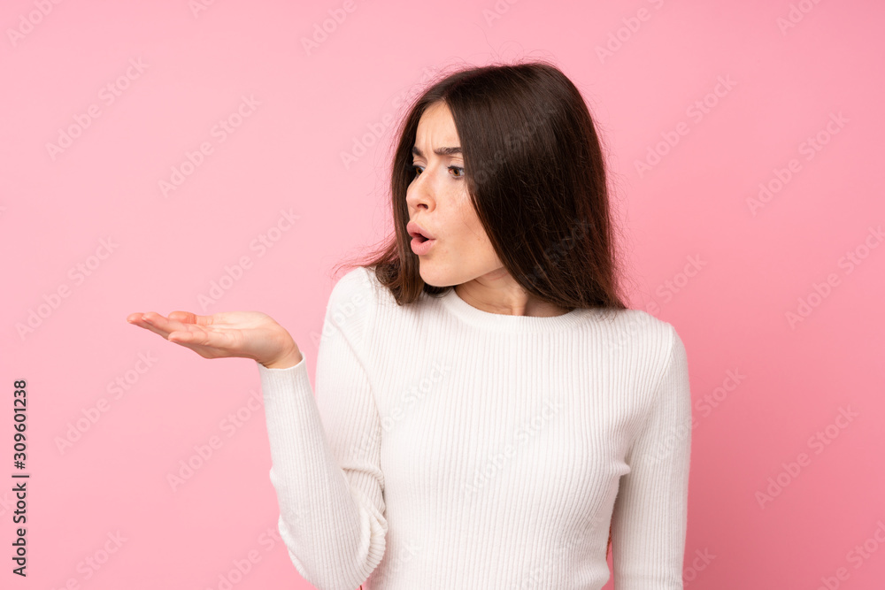 Young woman over isolated pink background holding copyspace imaginary on the palm Young woman over isolated pink background holding copyspace imaginary on the palm