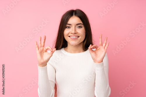 Young woman over isolated pink background showing an ok sign with fingers