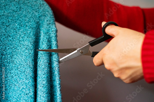 Woman dressed in red seamstress working on a blue piece of clothing.