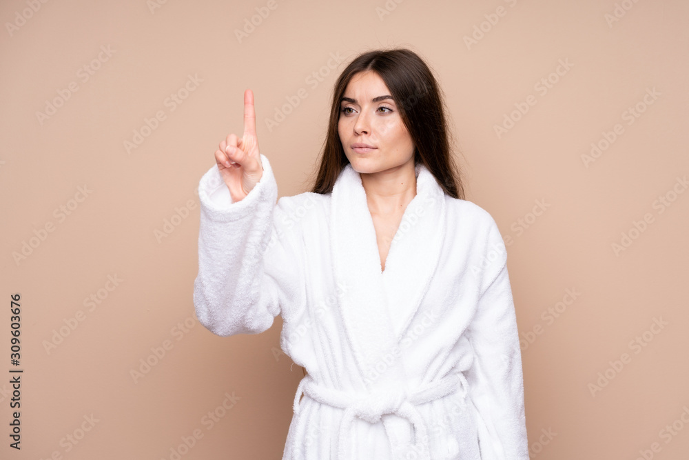 Young girl in a bathrobe over isolated background touching on transparent screen Young girl in a bathrobe over isolated background touching on transparent screen