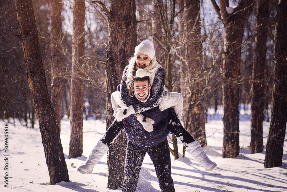 Fototapeta premium Guy and girl have fun in the forest in winter