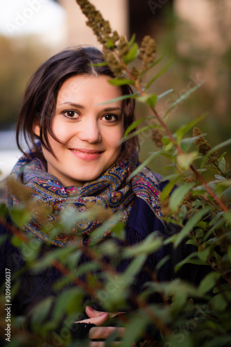 Beautiful young woman with black eyes while walking in a park. Autumn Walk. Female portrait. The girl is smiling. Woman enjoying the autumn nature. photo