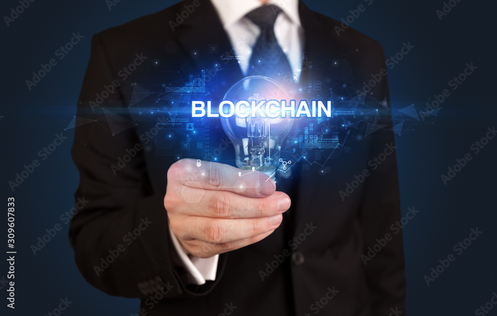 Businessman holding light bulb with BLOCKCHAIN inscription, innovative technology concept Businessman holding light bulb with BLOCKCHAIN inscription, innovative technology concept