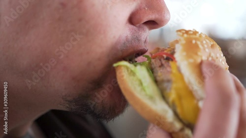 Man eating hamburger fast food, close-up