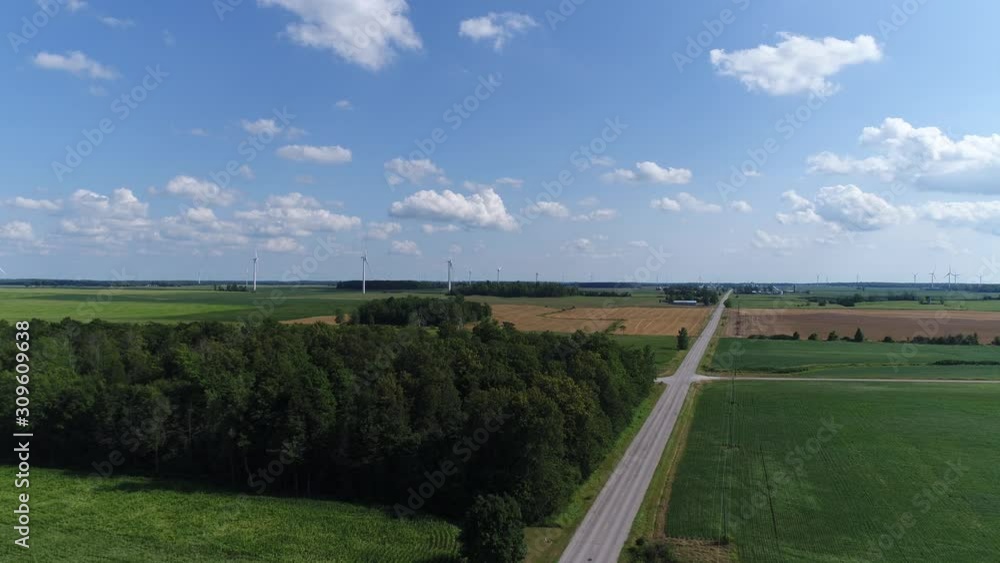 Flying Down Country Road Towards Green Forest And Green Fields And Energy Windmills Flying Down Country Road Towards Green Forest And Green Fields And Energy Windmills