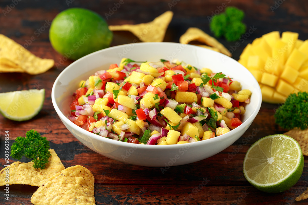 Bowl of fresh Mango Salsa with nachos chips and herbs. Healthy Vegan, Vegetables food. Bowl of fresh Mango Salsa with nachos chips and herbs. Healthy Vegan, Vegetables food.