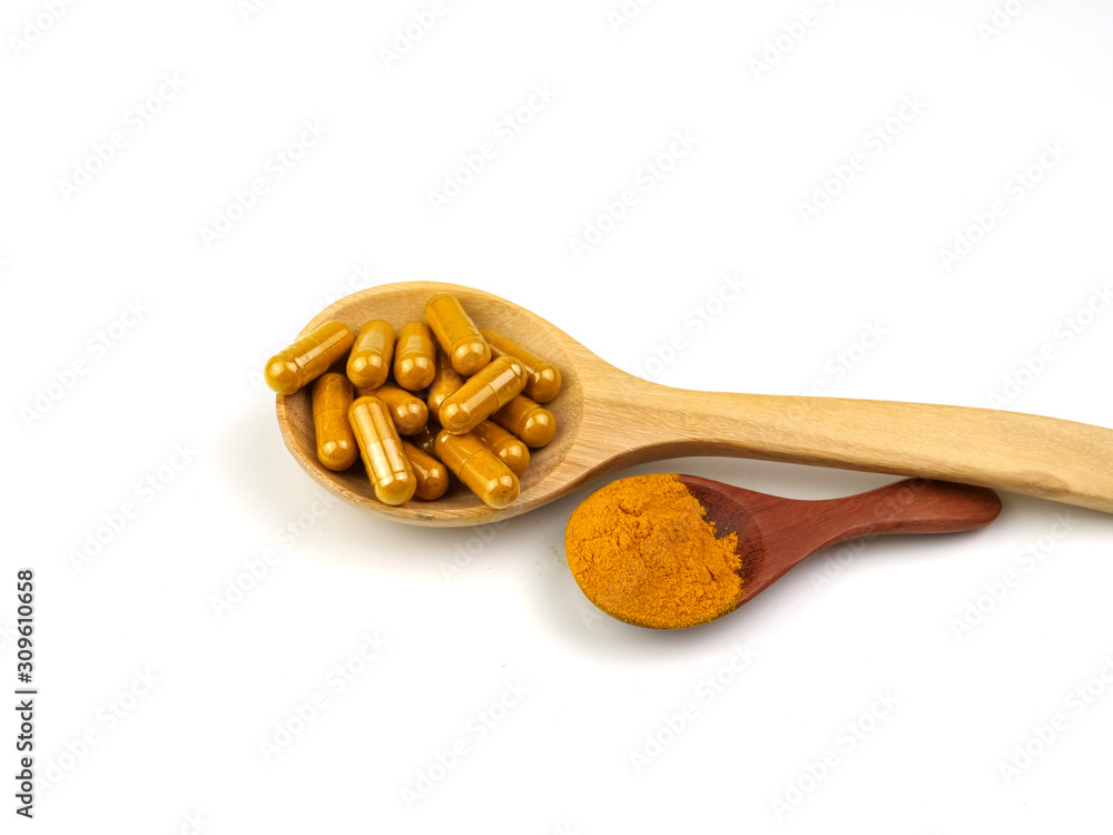 Turmeric capsules and powder in a spoon, isolated on a white background. Turmeric capsules and powder in a spoon, isolated on a white background.