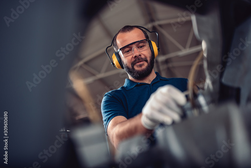 Photos Factory worker operating band saw cutting machine