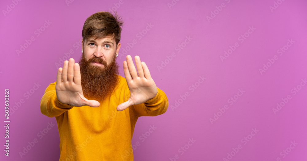 Redhead man with long beard over isolated purple background making stop gesture and disappointed Redhead man with long beard over isolated purple background making stop gesture and disappointed