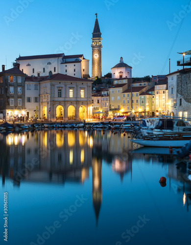 Night view of old city Piran in Slovenia. Beautiful cityscape through marina to Tartini Square.