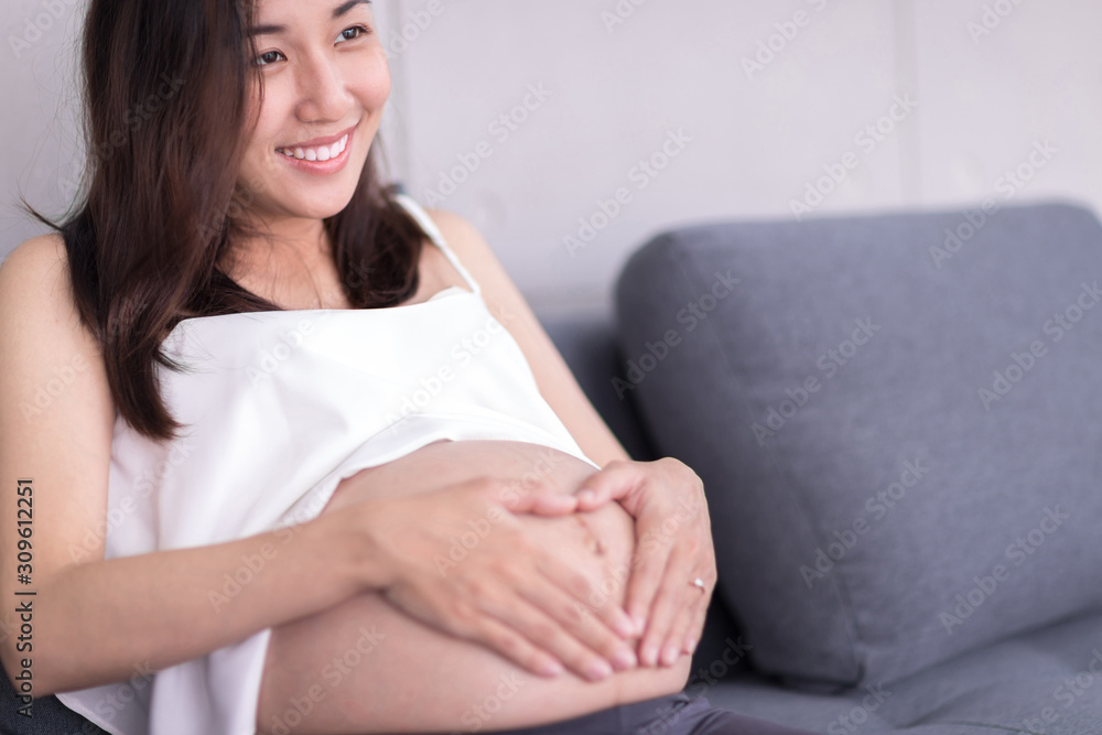 A pregnant woman is smiling hands touching their stomachs. A pregnant woman is smiling hands touching their stomachs.