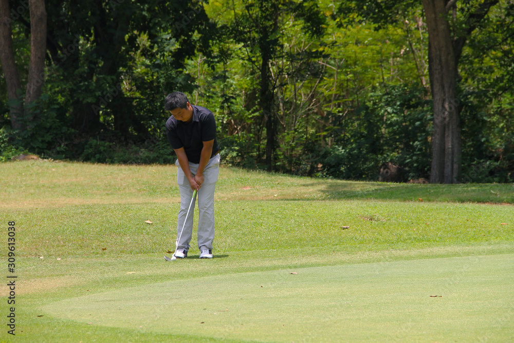 Obraz premium Golfer putting golf into the hole in beautiful golf course. The evening golf course with sunset in thailand