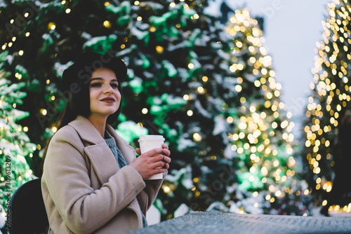 Young woman with paper cup near Christmas trees