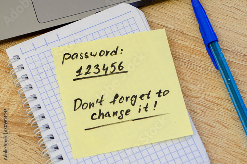 A very weak, simple and widespread password is written on a sticker that lies on a notebook next to a laptop. Password Security Weakness Concept. Bad password. Bad password policy.