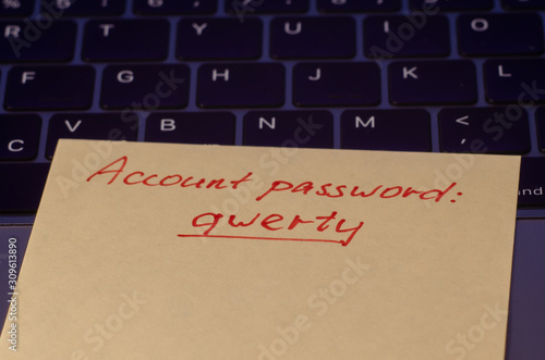 A very weak, simple and widespread password is written on a sticker that lies on the laptop keyboard. Password Security Weakness Concept. Bad password. Typical information security failures.  photo