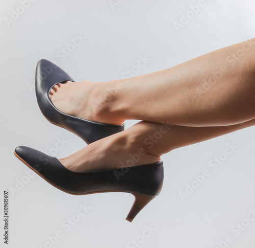 Slim female legs with classic high heel shoes on white background. Studio fashion shot