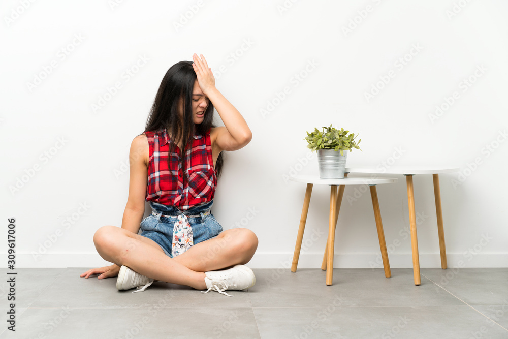 Teenager asian girl sitting on the floor having doubts with confuse face expression Teenager asian girl sitting on the floor having doubts with confuse face expression