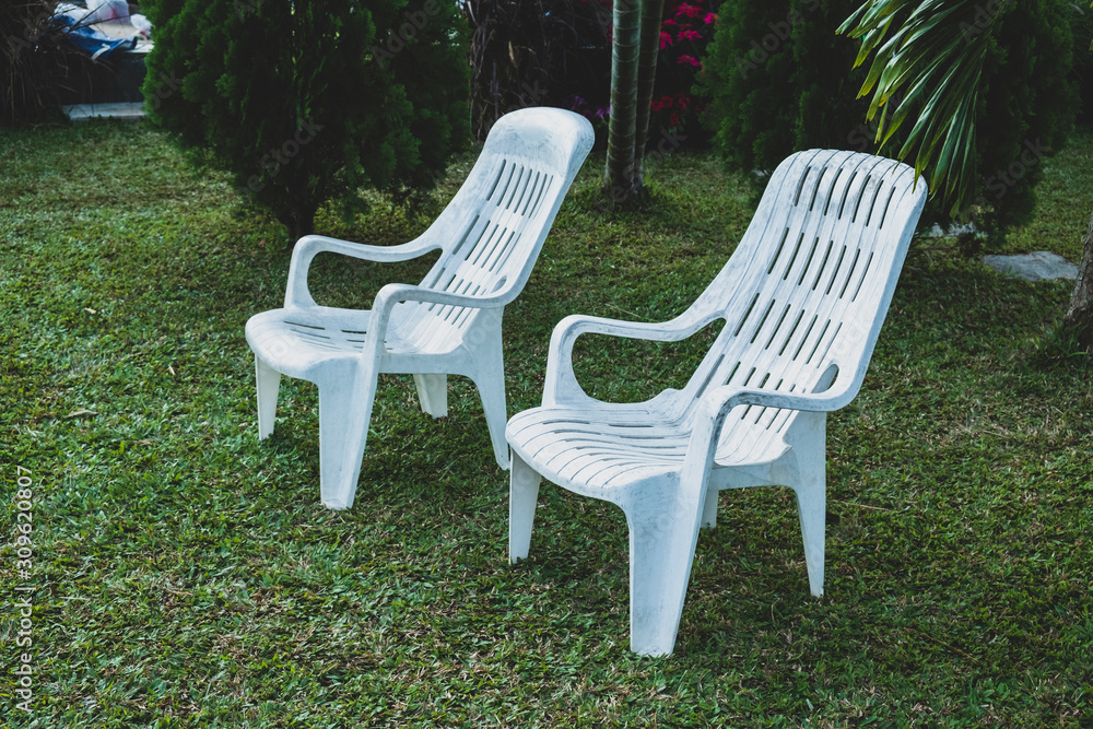 Close-Up Of Two white chairs On Grassy Field