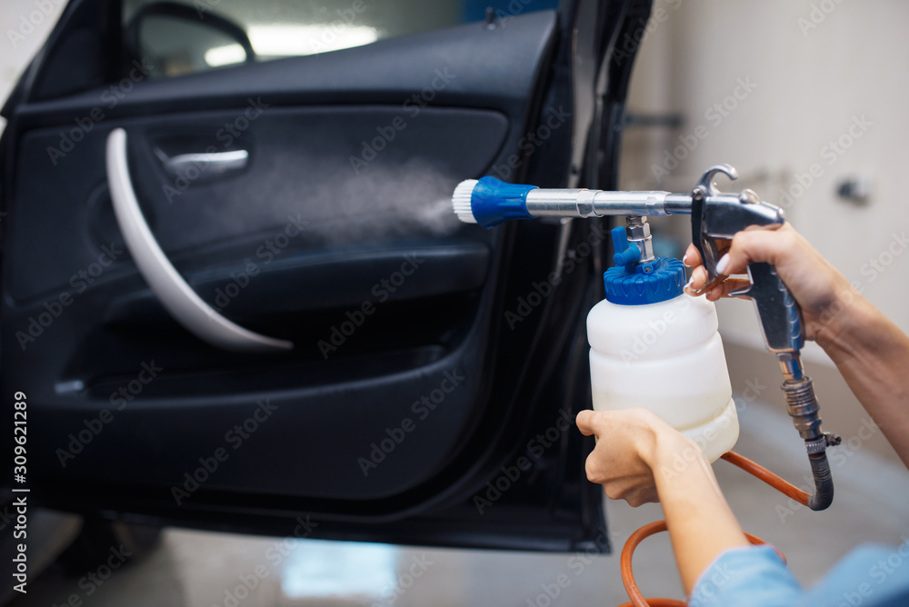 Female washer cleans automobile interior, car wash