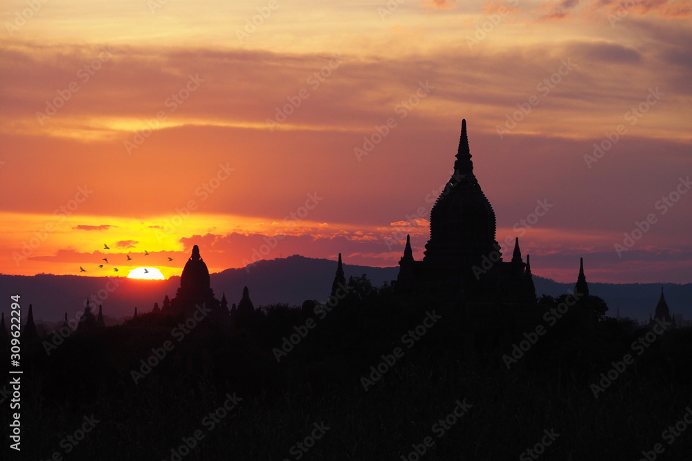Beautiful silhouette view of the old pagodas and Buddhist temples in Bagan Myanmar during sunset time with dark colorful and warm sky and mountain background. Religious landmark for tourism in Asia