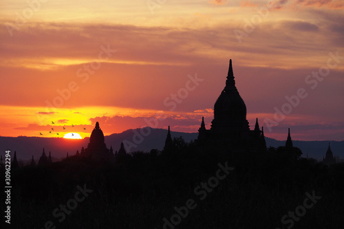 Beautiful silhouette view of the old pagodas and Buddhist temples in Bagan Myanmar during sunset time with dark colorful and warm sky and mountain background. Religious landmark for tourism in Asia © TS.PHOTOS
