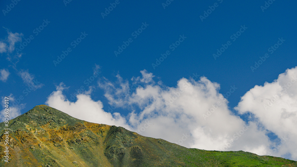 cumulus clouds over rock ridge, waiting for rain in mountain valley