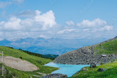 Turquoise lake among mountain peaks. High mountain river on summer day, hiking on rocks and stones